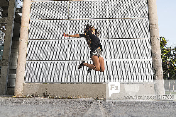 Überschwängliche junge Frau springt im Freien