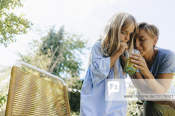 Mutter und Tochter teilen sich einen Smoothie im Garten