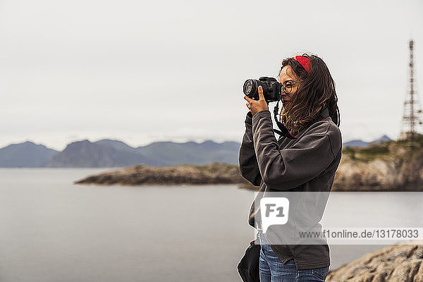 Young woman taking pictures of a lake in Vesteralen Island  Lapland  Norway