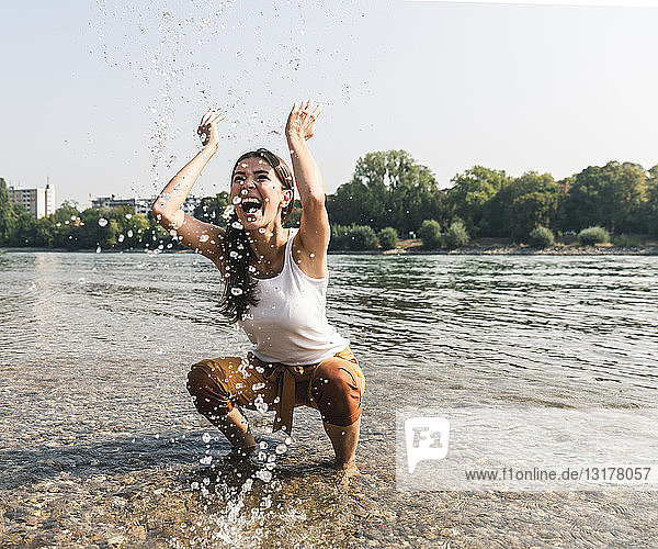 Unbeschwerte junge Frau  die sich im Wasser eines Flusses erfrischt