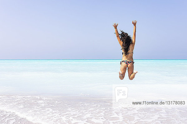Junge Frau springt am Strand