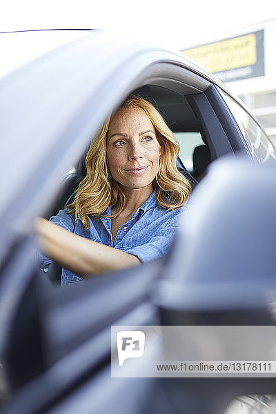 Lächelnde Auto fahrende Frau schaut aus dem Fenster