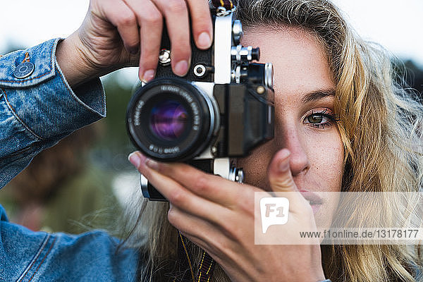 Close-up of beautiful blond young woman taking a picture with a camera