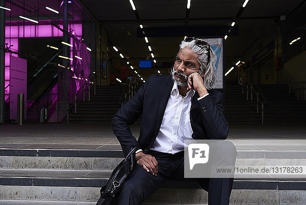 Stilvoller Senior-Geschäftsmann sitzt auf einer Treppe im Freien