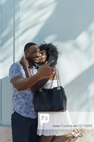 Lächelndes junges Paar  das sich umarmt und ein Selfie nimmt