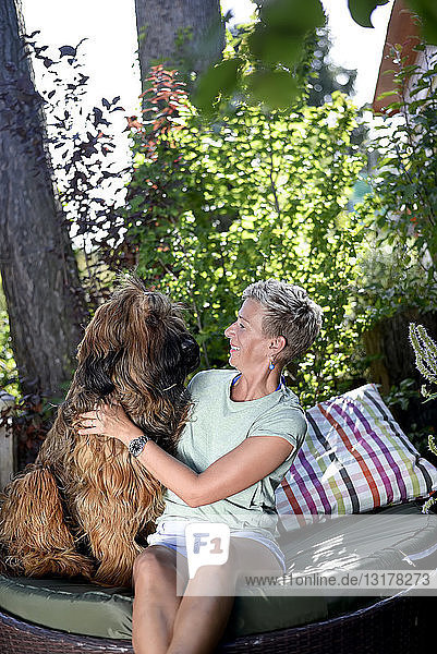 Lächelnde Frau mit ihrem Hund im Garten