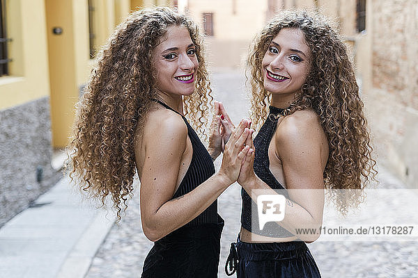 Porträt von glücklichen Zwillingsschwestern  die ihre Hände berühren