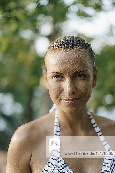 Porträt einer lächelnden Frau mit nassem Haar im Bikini