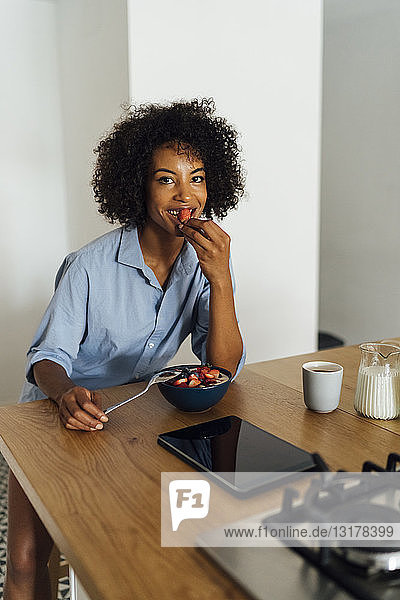Frau mit digitalem Tablet und gesundem Frühstück in ihrer Küche