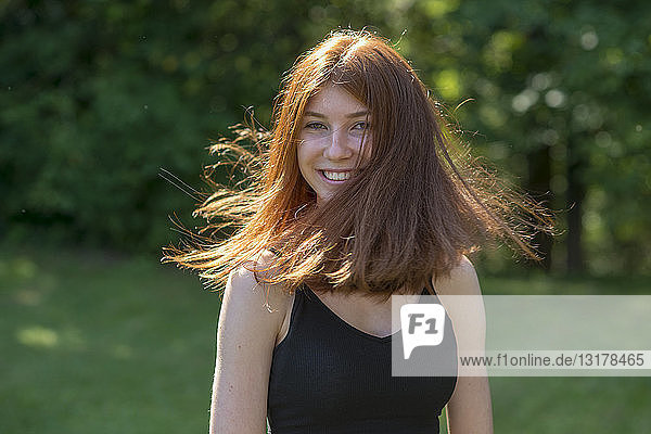 Porträt einer rothaarigen Teenagerin  die ihr Haar wirft