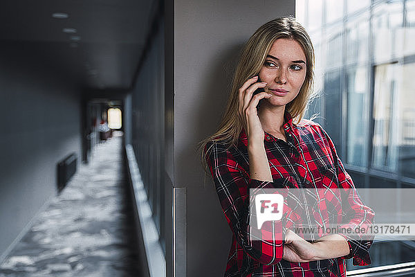 Porträt einer jungen Frau am Telefon in einem modernen Bürogebäude