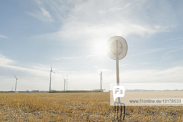 Heugabel im Feld in ländlicher Landschaft mit Windturbinen im Hintergrund