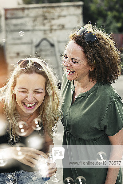 Zwei glückliche Frauen mit Seifenblasen im Freien