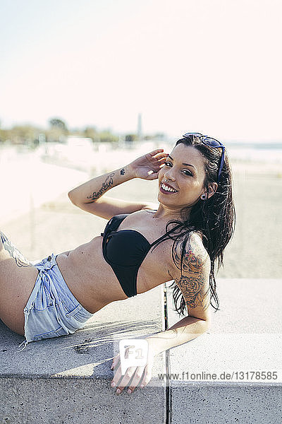 Portrait of young woman with nose piercing and tattoos relaxing at sunlight