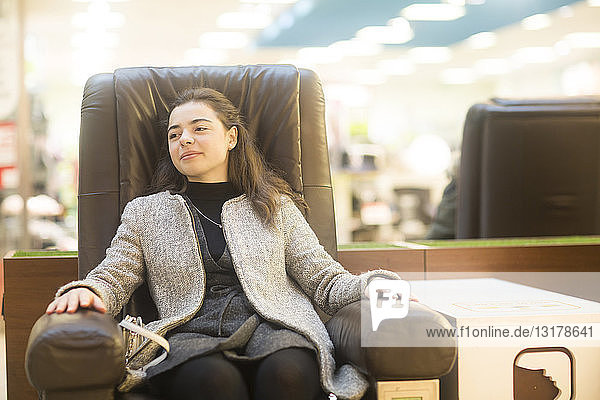 Porträt einer selbstbewussten jungen Frau  die sich in einem Lederstuhl in einem Geschäft ausruht