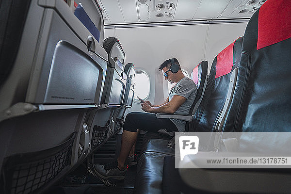 Mann im Flugzeug,  mit Smartphone,  Kopfhörer