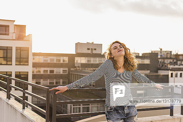 Young woman enjoying sunset on roof terrace