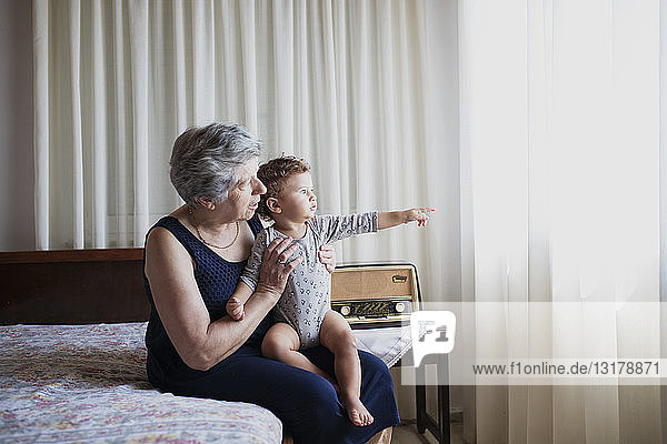 Grandmother sitting on bed with her grandson