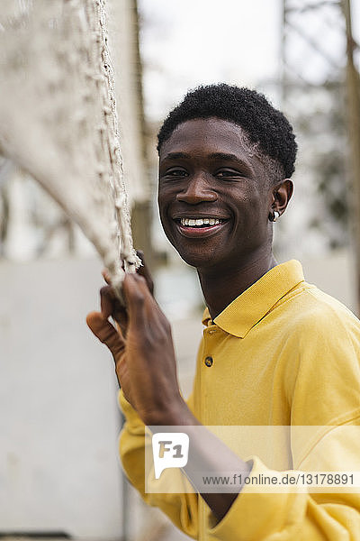 Porträt eines jungen schwarzen Mannes am Volleyballnetz stehend  lachend