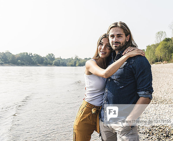 Glückliches junges verliebtes Paar umarmt sich am Flussufer