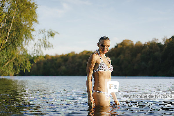 Porträt einer lächelnden Frau im Bikini in einem See