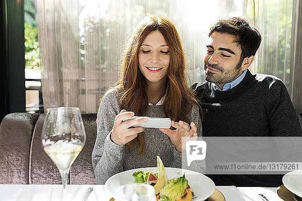 Smiling couple using cell phone in a restaurant
