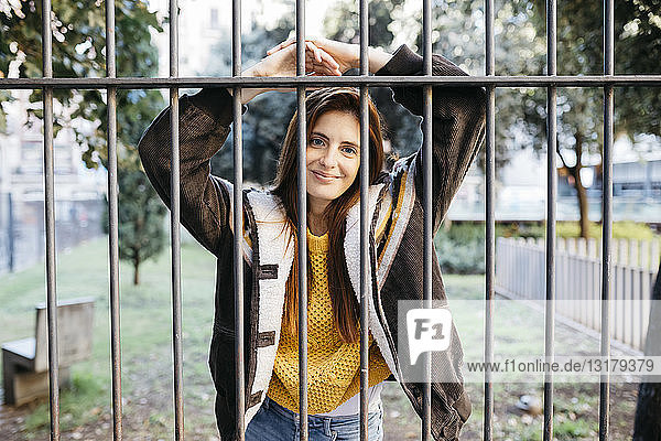 Red-haired smiling woman behind fence