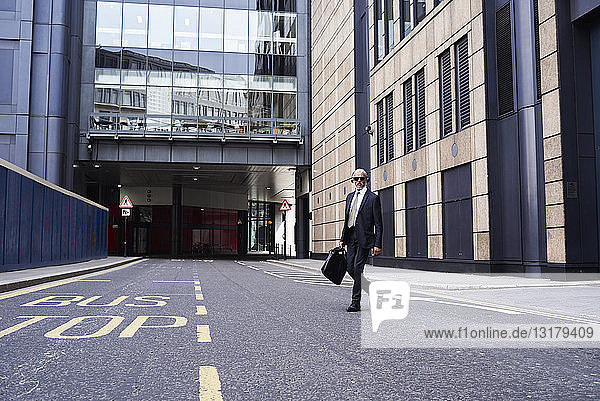 UK  London  senior businessman with headphones crossing the street
