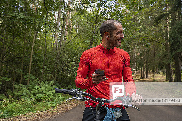 Mountainbiker mit Smartphone in einem Wald