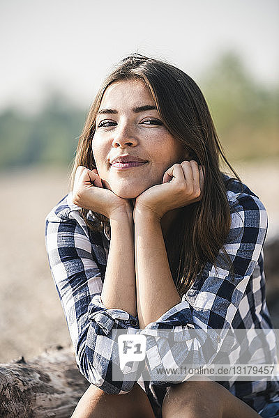 Porträt einer lächelnden jungen Frau  die im Freien sitzt
