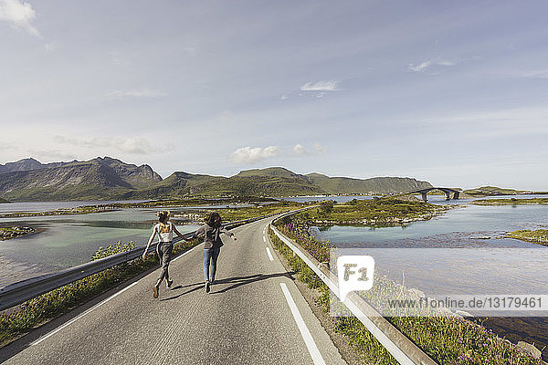 Junge Frauen gehen auf einer leeren Straße  Lappland  Norwegen