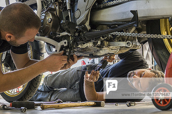 Mechanic working on motorcycle in workshop filmed by his partner