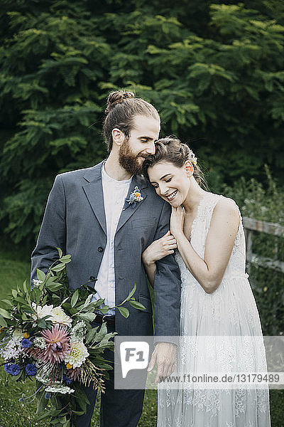 Happy affectionate bride and groom standing on a meadow