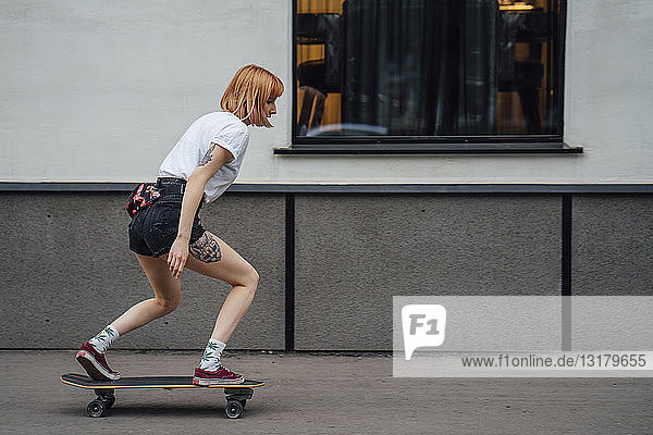 Junge Frau fährt Carver-Skateboard auf dem Bürgersteig
