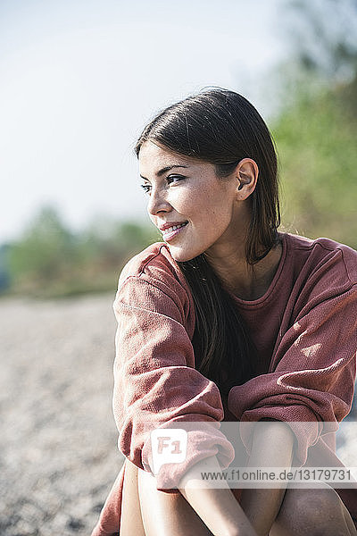 Lächelnde junge Frau sitzt im Freien