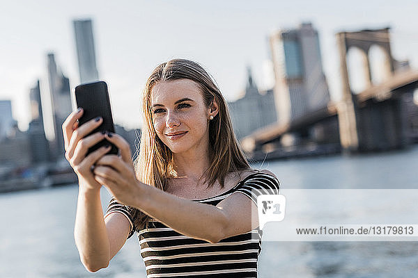 USA  New York  Brooklyn  Porträt einer jungen Frau  die mit einem Smartphone Selbsthilfe betreibt