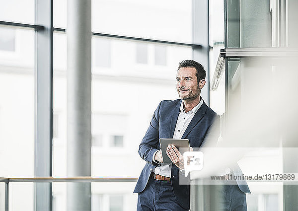 Businessman standing in office building  using digital tablet