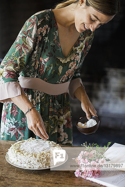 Lächelnde junge Frau garniert selbstgebackenen Kuchen