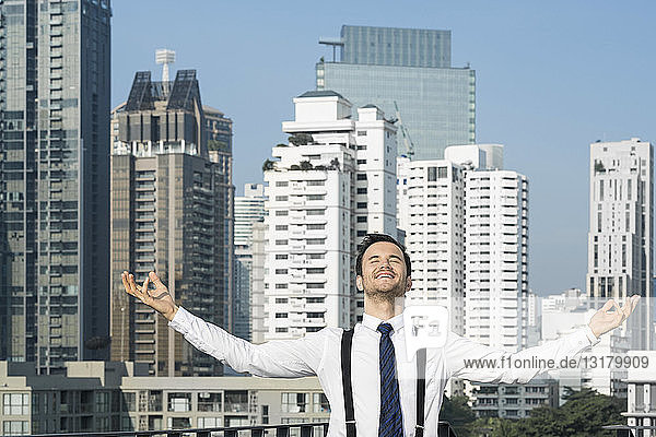 Happy and content successful business man on city rooftop