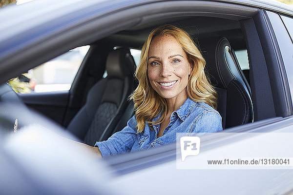 Porträt einer lächelnden Frau  die Auto fährt und aus dem Fenster schaut