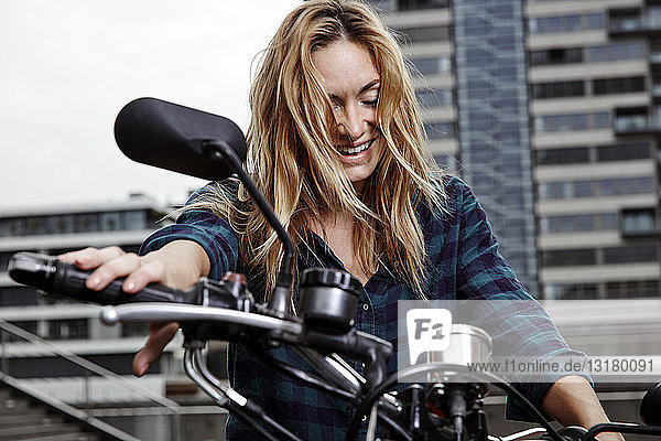 Lachende junge Frau auf Motorrad