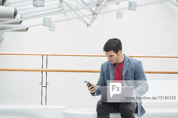 Geschäftsmann in der Lobby eines modernen Gebäudes mit Smartphone