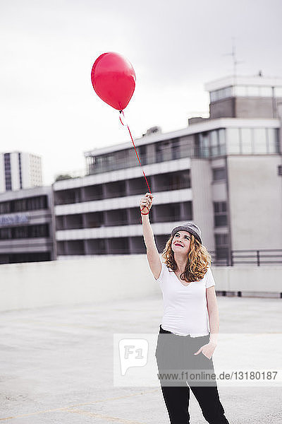 Lächelnde junge Frau mit rotem Ballon