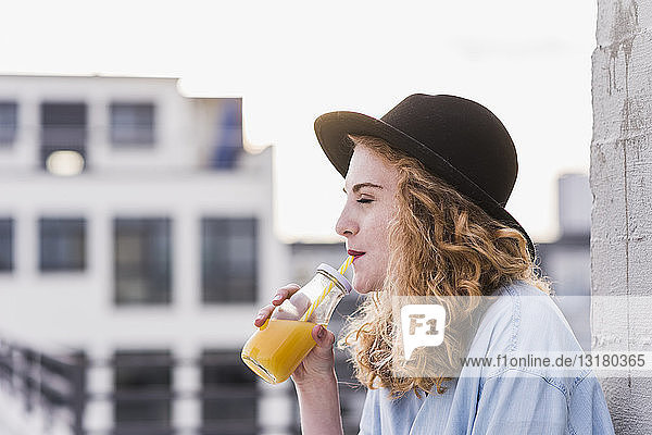 Porträt einer jungen Frau mit Hut  die ein Getränk trinkt