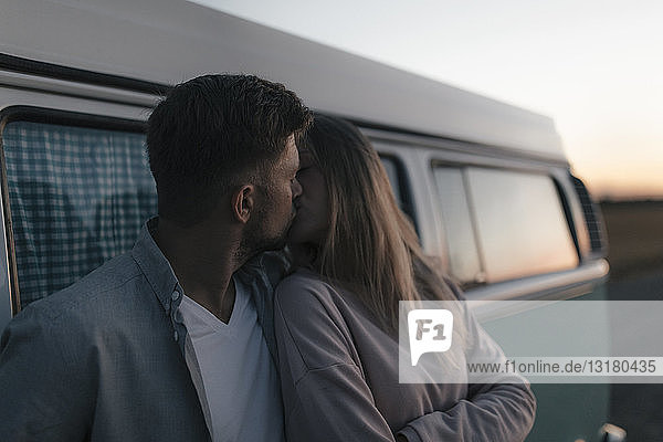 Junges Paar küsst sich in der Abenddämmerung im Wohnmobil