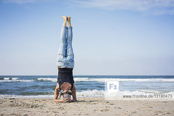 Mature woman doing a headstand on the beach
