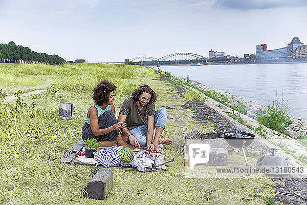 Deutschland  Köln  Ehepaar beim Grillen am Flussufer