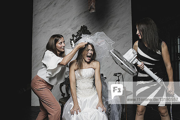 Playful friends and bride during wedding preparation