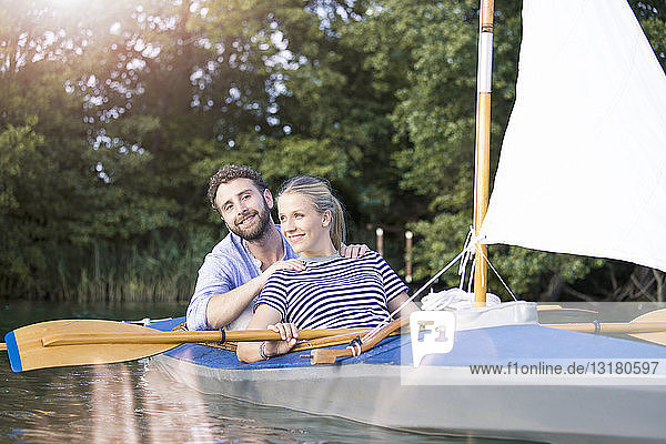 Happy young couple enjoying a trip in a canoe with sail