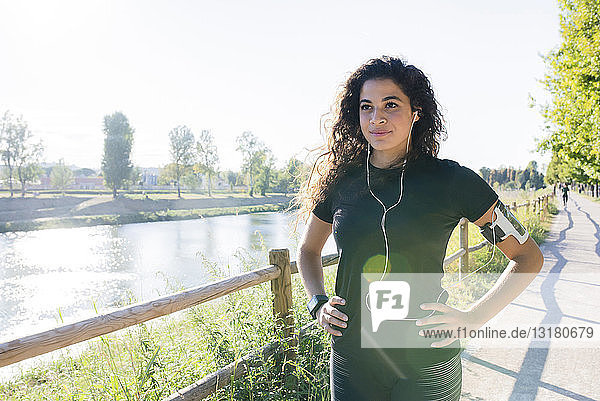 Sportliche junge Frau macht eine Pause am Flussufer